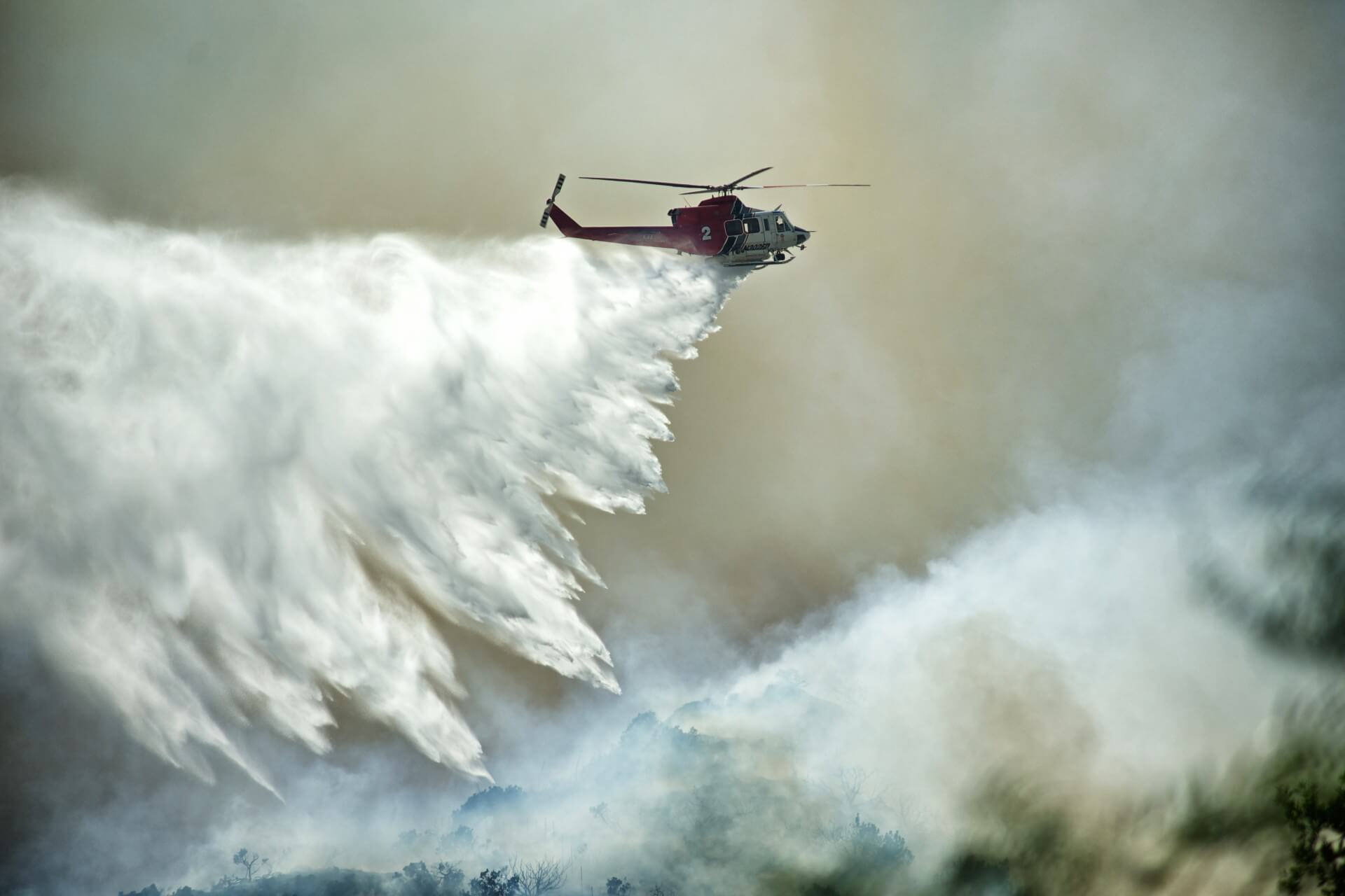 A helicopter drops water on a wildfire in an attempt to extinguish or at least control the spread of the flames.